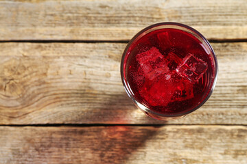 Sweet soda water with ice cubes in glass on wooden table, top view. Space for text
