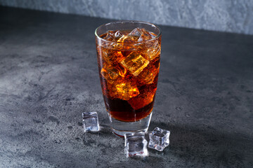Sweet soda water in glass with ice cubes on grey table