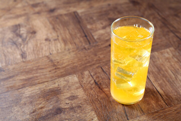 Sweet soda water with ice cubes in glass on wooden table. Space for text