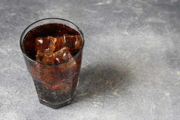 Refreshing cola with ice cubes in glass on light textured table, closeup. Space for text