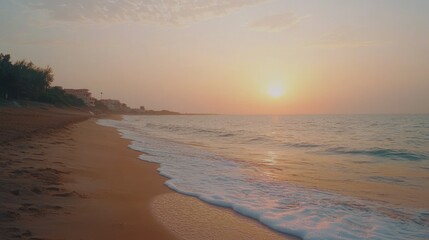 Obraz premium Serene sunset over sandy beach with gentle waves.