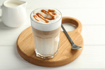 Tasty latte macchiato in glass on white wooden table, closeup
