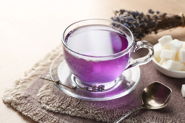 Aromatic lavender tea in glass cup and spoon on wooden table, closeup