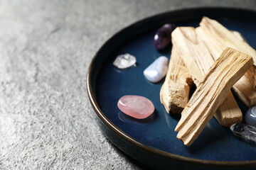 Palo santo sticks and gemstones on grey table, closeup