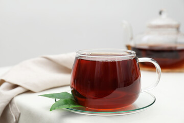 Refreshing black tea in cup on light table, closeup