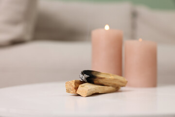 Palo santo sticks and burning candles on white table indoors, space for text