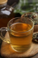 Delicious herbal tea and dry leaves on wooden table, closeup