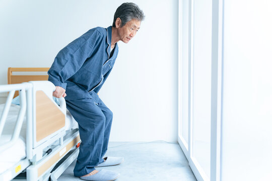シニア、男性、膝痛、入院、患者、ベッド、介護、高齢者、日本人、立つ、立ち上がる、ひざ、リハビリ、老人、お年寄り、福祉、施設、介護ベッド、病院、寝室、パジャマ、フレイル、ロコモティブシンドローム、DHA、ミドル、60代、50代、中高年、中年、治療、早朝、健康、ヘルスケア、明るい、立ち上がり、筋力、練習、手すり、ADL練習、ライフスタイル、室内、下肢、QOL、ADL、老化、加齢、サプリメント、健康食品
