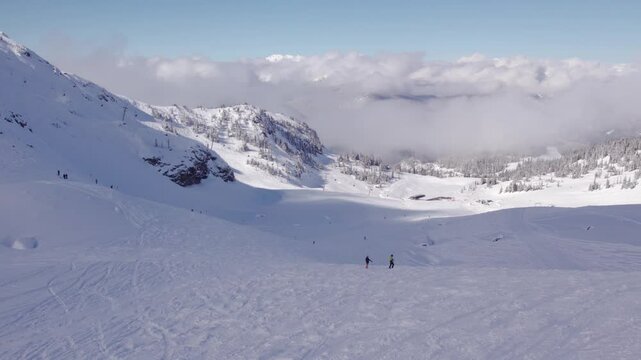 Downhill skiers with mountain vista, aerial footage, ski mountain, sunny day, winter, ski hill, Whistler BC. 5.4K 24FPS