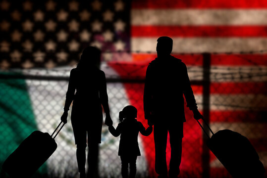 A family stands in front of a fence on the Mexican-American border