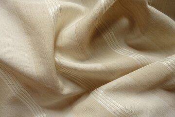 Soft folds on light beige striped cotton and polyester fabric