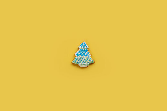 Gingerbread Christmas cookie with white and blue icing garlands on a yellow background