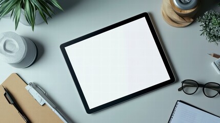 Digital Workspace: A top-down view of a modern digital workspace, featuring a tablet with a blank screen, surrounded by office supplies like pens, notebooks, and greenery.