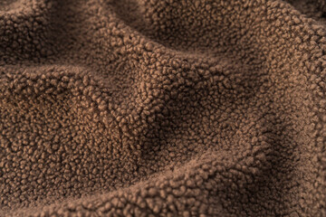A snug and fluffy fleece teddy recycled polyester fabric texture in brown, capturing warmth and coziness. Perfect for backgrounds, fashion materials, and interior design.