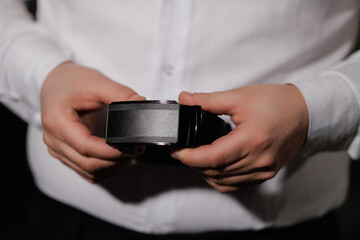 A man is holding a belt in his hand. The belt is black and has a silver buckle. The man is wearing...