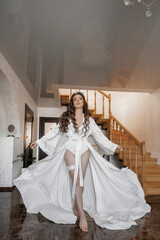 Fototapeta premium A woman in a white gown is standing on a staircase. She is wearing a headband and has her arms outstretched. Concept of elegance and grace, as the woman is dressed for a special occasion