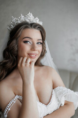 A woman wearing a tiara and a white dress is smiling. She is wearing a ring on her finger