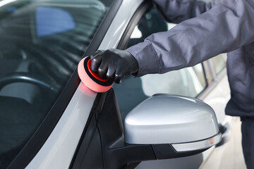 Man polishing car with sponge indoors, closeup