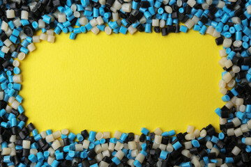 Frame of colorful plastic granules on yellow background, top view. Space for text