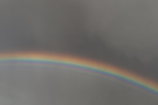 Vibrant colorful rainbow arcing against a dark dramatic stormy sky