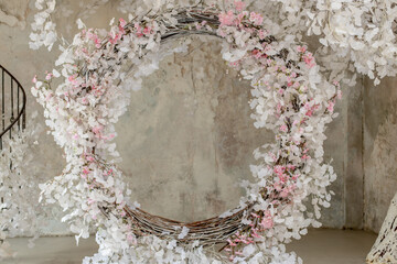 Arch decorated with artificial sakura flowers against the background of old concrete walls, loft-style interior, decor and decorations for a photo shoot room