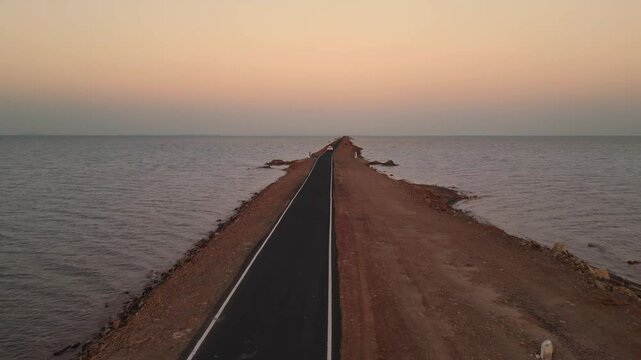 A breathtaking view of the Road to Heaven in Kutch, Gujarat, where a stunning stretch of road cuts through the sea on both sides. As the sun sets, golden hues paint the sky 4K Drone