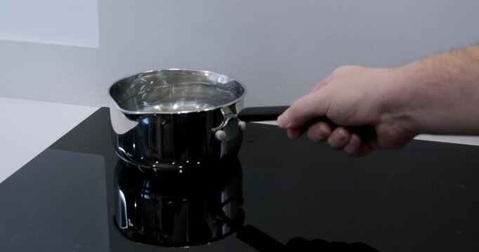 putting a pan of water onto a induction hob and the water boiling away