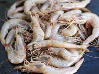 Close up of a pile of large fresh shrimps placed on a wooden board