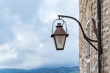 A street lamp is hanging from a stone wall in Gubbio Italy Umbria