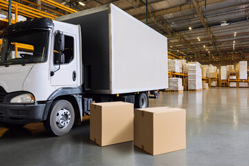 Naklejka premium A truck unloads boxes in a warehouse, demonstrating logistics and transportation operations