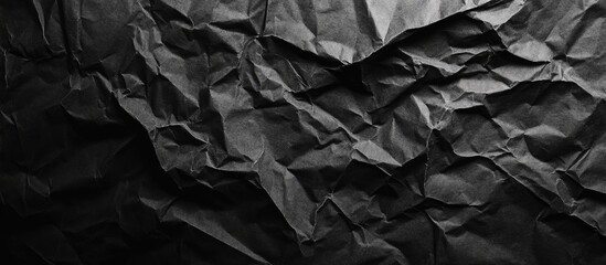 Crumpled black paper background with deep folds and texture creating a grunge effect capturing shadows and highlights for artistic use