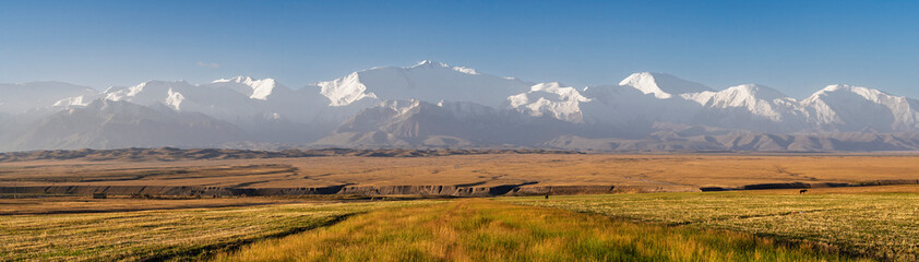 Scenic rural landscape panorama after sunrise of snowcapped Trans Alay mountain range with Lenin...