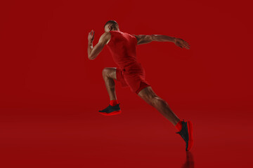 Dynamic composition. Sprinter in red accelerating into motion, power and agility radiating against vivid background. Concept of sport, energy, fitness, endurance, speed, competition.