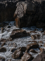 Close up view how Atlantic ocean wave breaks on the big rocky stone on the beautiful volcanic beach of portugal