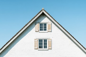 White house with wooden shutters under clear blue sky showcasing traditional architectural style and design elements during daylight hours