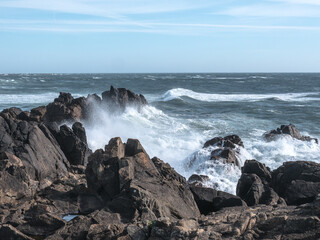 Close up view how Atlantic ocean wave breaks on the big rocky stone on the beautiful volcanic beach of portugal