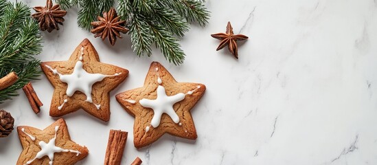Star-shaped Christmas cookies with white icing, surrounded by fir tree twigs and star anise, on a white marble table, viewed from above.