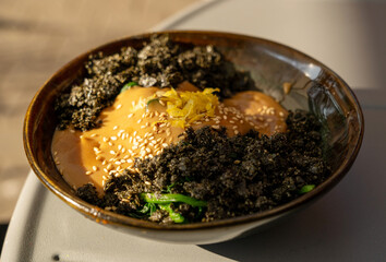 Vegetarian spinach salad closeup. Fried spinach with nori and tahini, vegan dish in sunlight