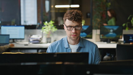 Focused man looking desktop working at open space closeup. Smiling freelancer