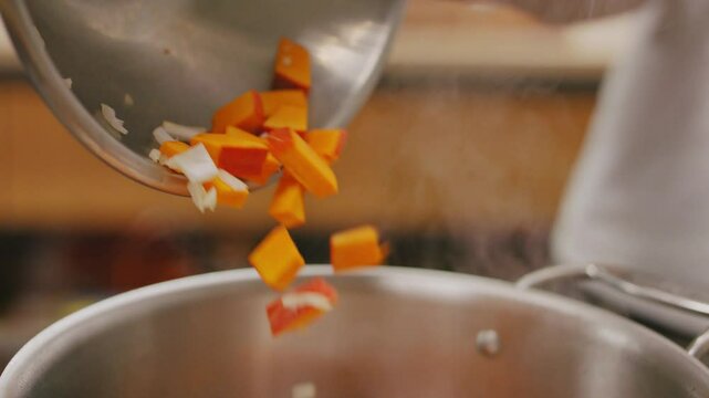 Man sch&uuml;ttet Zwiebel, Karotten Gemisch aus Aluminium Sch&uuml;ssel in hei&szlig;en Topf im Close Up Gesunder Lifestyle mit gesunder Ern&auml;hrung, leckerem und gesundem Essen, Vegane Mahlzeit