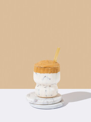 Korean whipped drink Dalgona coffee in a glass on a marble stand on a white beige background.