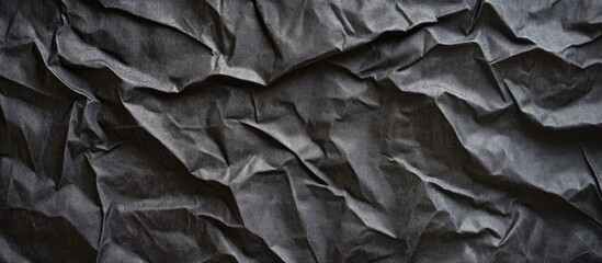 Crumpled black paper background showcasing deep black tones and intricate textured patterns for versatile design applications and creative projects.
