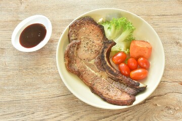 grilled black pepper pork chop steak and lettuce with tomato couple boiled carrot on plate dipping barbecue sauce in cup