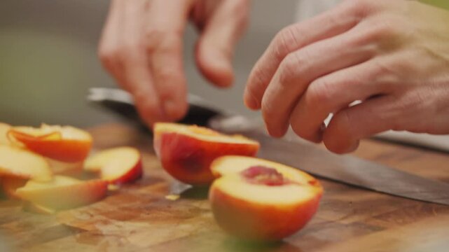 Koch bereitet Pfirsich zu auf Holzbrett mit Messer in K&uuml;che schneidet Obst mit H&auml;nden