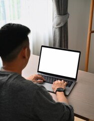 young man using computer laptop in front of an blank white computer screen