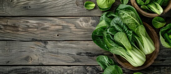 Fototapeta premium Fresh bok choy arranged in wooden bowls on a rustic wooden table with textured gray planks creating ample copy space on the right side