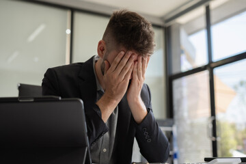 Businessman male stressed over credit card debt monthly expenses in office.