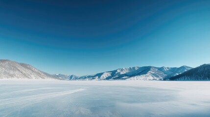 Expansive Winter Landscape with Frozen Lake Surrounded by Snow-Capped Mountains Under Clear Blue Sky