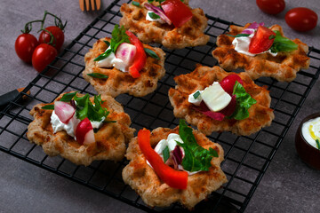 Cheese waffles with vegetables and sour cream sauce on a serving rack. Lenten and vegetarian dish