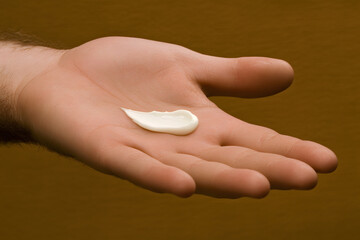 Gentle moisturizer rests on a hand, showcasing its creamy texture and sheen against a warm backdrop